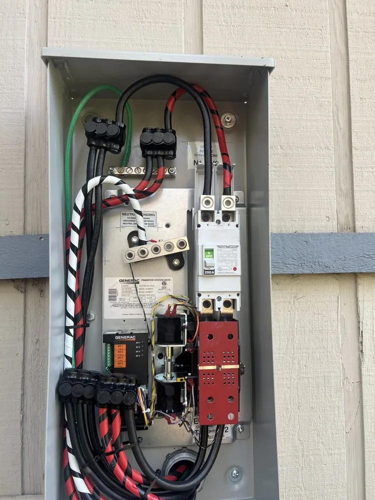 Open main service panel with new breakers and neatly routed red and black conductors.